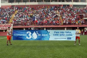 Jogadores exibem faixa da Copasa, da campanha "Cada gota conta", no estádio Farião, em Divinóplis