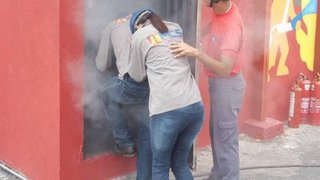 Brigadistas entram na casa de fumaça, que simula um prédio em chamas