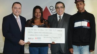 Juliana Alves Coelho, da cidade de Presidente Kubitschek, recebe cheque simbólico do Banco Travessia